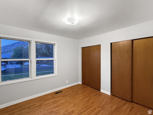 1066 Beecher Ave, Brigham City, UT 84302 - unfurnished bedroom featuring multiple closets, light wood finished floors, and baseboards