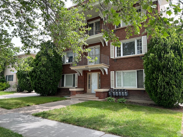 823 E 23rd St S, Ogden, UT 84401 - view of front of house with brick siding, a front lawn, and a balcony