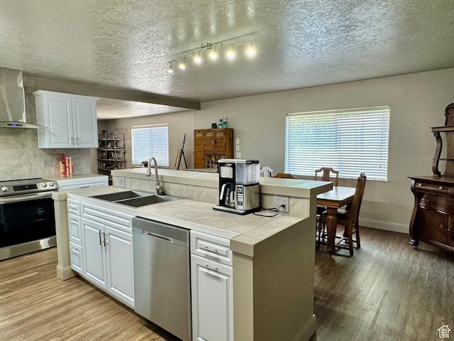 160 W 100 S, Fillmore, UT 84631 - kitchen with stainless steel appliances, a sink, wall chimney exhaust hood, light wood-style flooring, and a textured ceiling