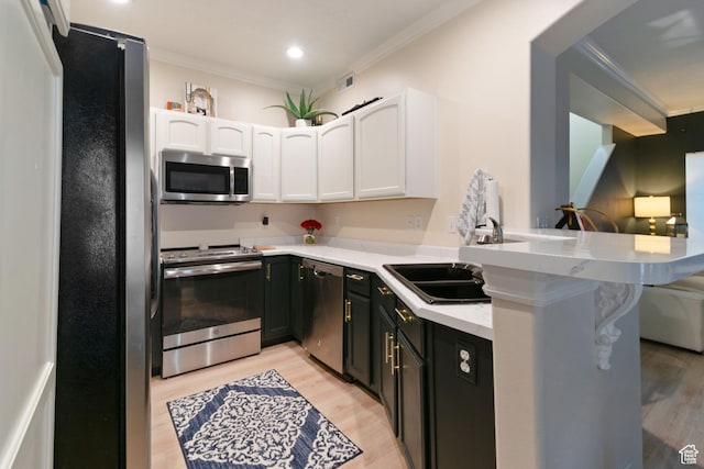 1559 W Alsace Way, West Valley City, UT 84119 - kitchen featuring appliances with stainless steel finishes, white cabinets, crown molding, light wood-style flooring, and a peninsula
