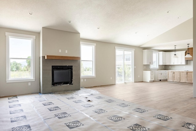 1928 E 540 S, Heber City, UT 84032 - unfurnished living room with a fireplace, plenty of natural light, light wood-style flooring, lofted ceiling, and a textured ceiling