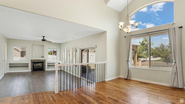9677 S Iron Gate Rd, South Jordan, UT 84095 - unfurnished living room with a chandelier, wood-type flooring, baseboards, ceiling fan, and a stone fireplace