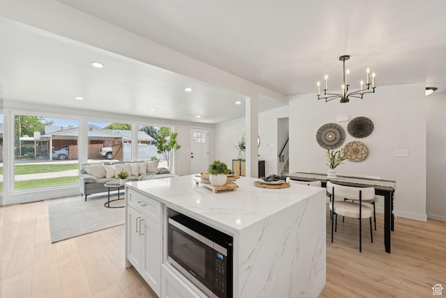 4194 S Bennion Rd, Taylorsville, UT 84129 - kitchen with stainless steel microwave, light wood-style floors, open floor plan, a kitchen island, and white cabinets
