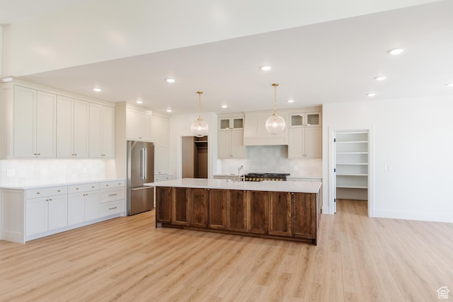 435 E 200 N, Millville, UT 84326 - kitchen featuring high quality fridge, light wood-style flooring, tasteful backsplash, light countertops, and a large island with sink
