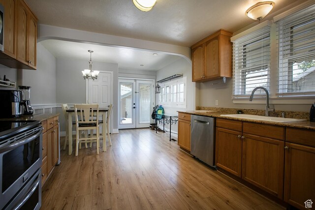1438 E Woodland Ave S, Millcreek, UT 84106 - kitchen featuring appliances with stainless steel finishes, arched walkways, brown cabinets, and light stone counters