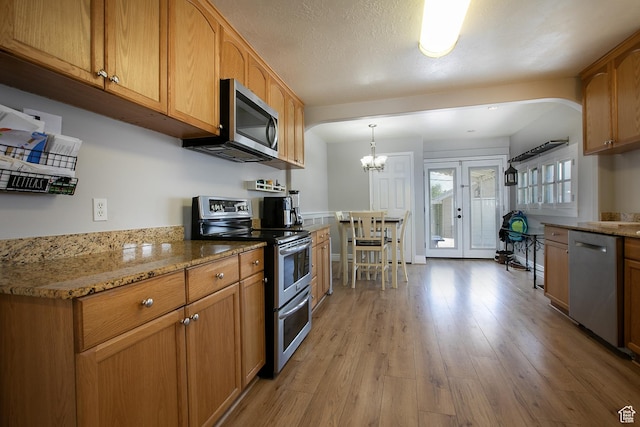 1438 E Woodland Ave S, Millcreek, UT 84106 - kitchen with stainless steel appliances, light wood-style floors, light stone counters, and french doors