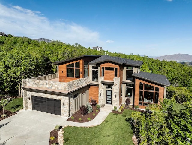 1040 S Summit Creek Dr, Woodland Hills, UT 84653 - modern home featuring stone siding, a balcony, driveway, a front yard, and a mountain view
