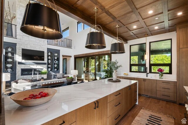 1040 S Summit Creek Dr, Woodland Hills, UT 84653 - kitchen with wooden ceiling with exposed beams, brown cabinetry, open floor plan, dark wood-style flooring, and light stone countertops