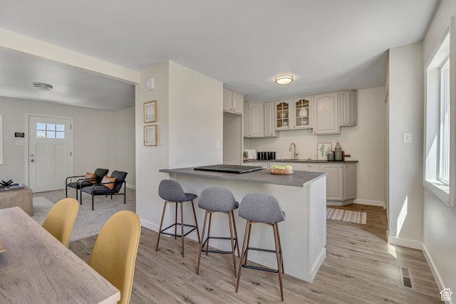 4401 W 5655 S, Salt Lake City, UT 84118 - kitchen with a breakfast bar, glass insert cabinets, baseboards, and light wood-style floors