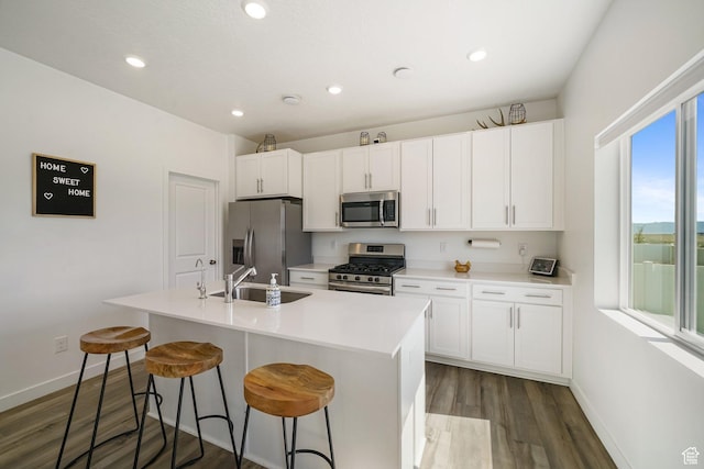 3493 N Sparrow Ln, Eagle Mountain, UT 84005 - kitchen featuring appliances with stainless steel finishes, dark wood-style floors, an island with sink, white cabinetry, and a breakfast bar area