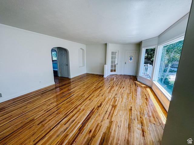 1516 E 36th, Ogden, UT 84403 - unfurnished room featuring arched walkways, hardwood / wood-style floors, baseboards, crown molding, and a textured ceiling