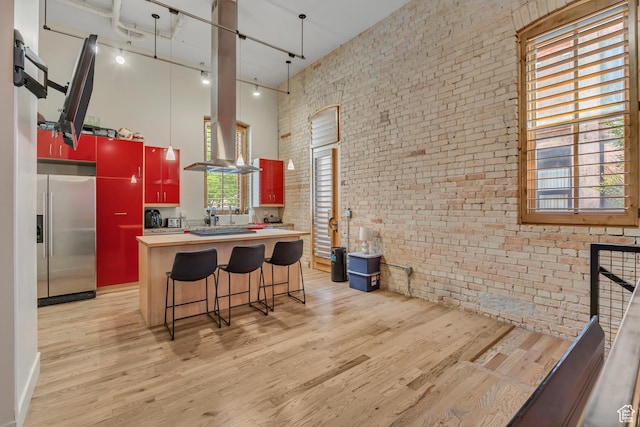 342 W 200 S Unit 107, Salt Lake City, UT 84101 - kitchen with stainless steel fridge, a towering ceiling, brick wall, light wood-style flooring, and track lighting