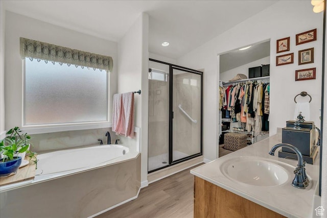 4034 Fortune Way, Washington, UT 84780 - full bathroom featuring a stall shower, wood finished floors, a garden tub, vanity, and a walk in closet
