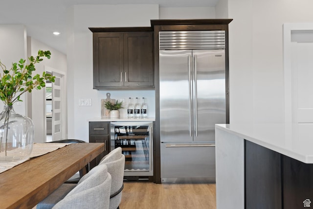 915 E 2100 N, North Ogden, UT 84414 - kitchen with built in refrigerator, wine cooler, dark brown cabinets, light wood-type flooring, and light countertops
