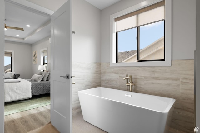 915 E 2100 N, North Ogden, UT 84414 - ensuite bathroom with tile walls, a freestanding bath, a ceiling fan, wainscoting, and wood finished floors
