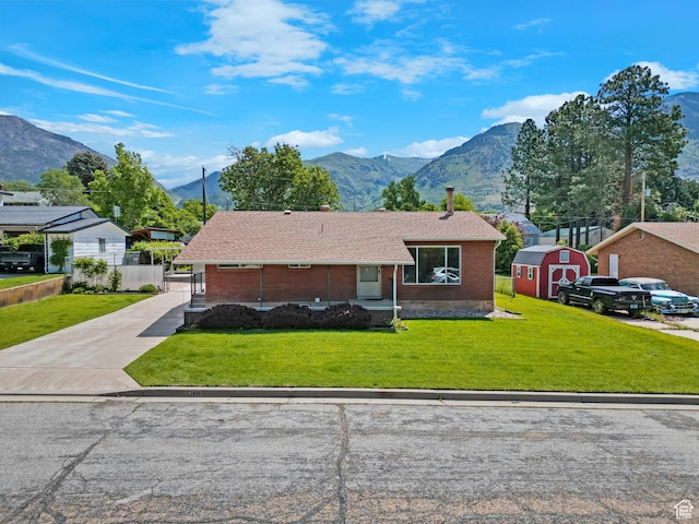 2458 N 575 E, North Ogden, UT 84414 - view of front of house with a mountain view, a front yard, brick siding, concrete driveway, and a shingled roof