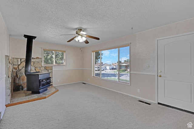 2458 N 575 E, North Ogden, UT 84414 - unfurnished living room featuring a ceiling fan, a textured ceiling, carpet flooring, a wood stove, and baseboards