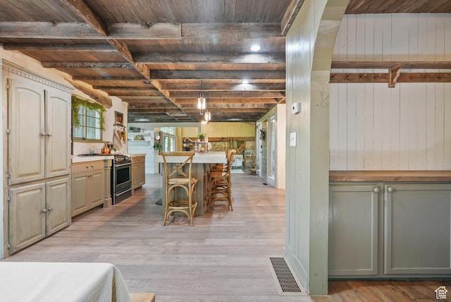 153 W 4350 N, Pleasant View, UT 84414 - kitchen with stainless steel stove, wooden ceiling with exposed beams, light wood-style flooring, a kitchen bar, and wood walls