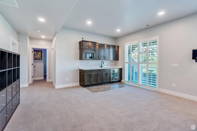 15058 S Spring Canyon Dr, Herriman, UT 84096 - indoor wet bar featuring recessed lighting, baseboards, light carpet, stainless steel microwave, and beverage cooler