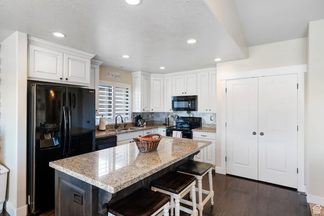 3547 E Jacobs Way, Eagle Mountain, UT 84005 - kitchen featuring black appliances, a sink, white cabinetry, dark wood-style flooring, and a kitchen bar
