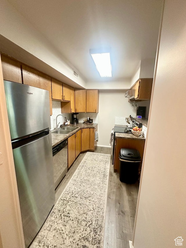 1175 S Canyon Rd E Unit 81, Ogden, UT 84404 - kitchen with appliances with stainless steel finishes, a sink, light wood-style flooring, wall chimney exhaust hood, and brown cabinets