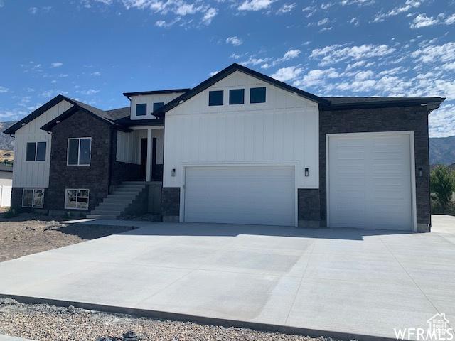 3323 N 1200 W, Pleasant View, UT 84414 - view of front facade with a garage, stone siding, driveway, and board and batten siding