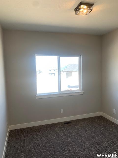 3323 N 1200 W, Pleasant View, UT 84414 - empty room featuring dark colored carpet, healthy amount of natural light, and baseboards