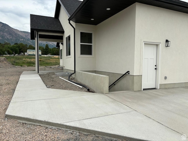 3323 N 1200 W, Pleasant View, UT 84414 - view of exterior entry featuring a mountain view, stucco siding, a patio, and a shingled roof