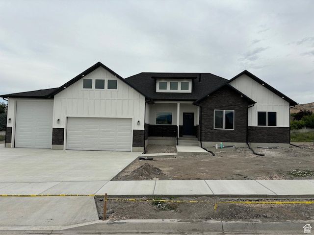 3323 N 1200 W, Pleasant View, UT 84414 - view of front of house featuring a garage, driveway, board and batten siding, a shingled roof, and brick siding