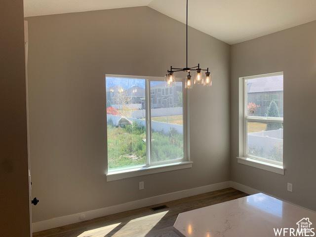 3323 N 1200 W, Pleasant View, UT 84414 - unfurnished dining area with plenty of natural light, a chandelier, wood finished floors, vaulted ceiling, and baseboards