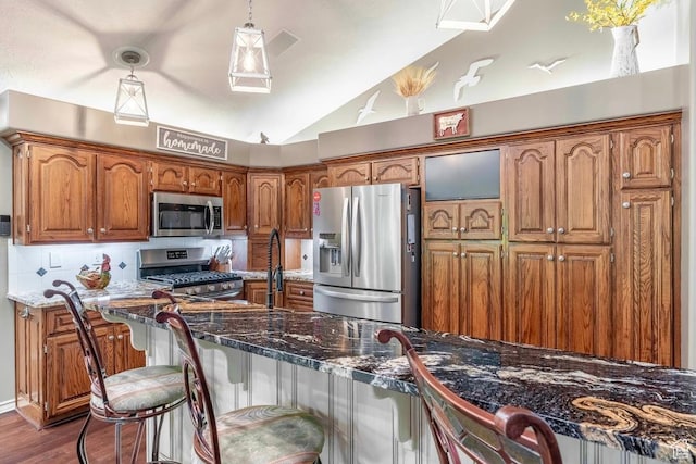4862 S Kiwana Dr, South Ogden, UT 84403 - kitchen with stainless steel appliances, vaulted ceiling, brown cabinets, decorative backsplash, and dark wood-style floors