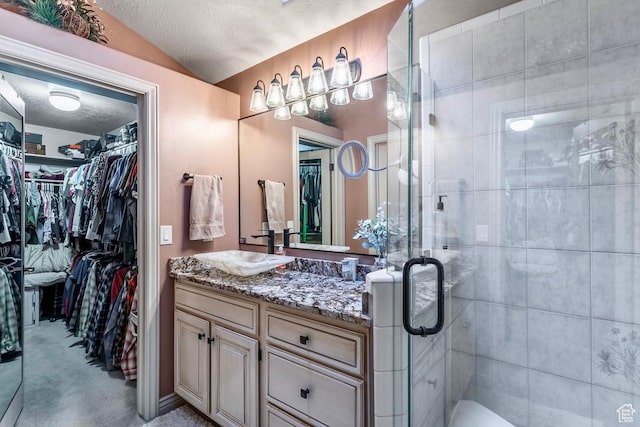 4862 S Kiwana Dr, South Ogden, UT 84403 - bathroom with vanity, a spacious closet, a shower stall, a textured ceiling, and lofted ceiling