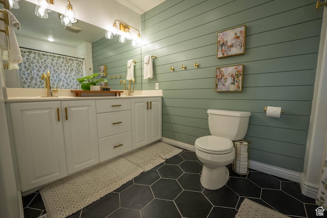 1536 E Mountain Rd, Logan, UT 84321 - bathroom with double vanity, toilet, baseboards, wood walls, and tile patterned flooring