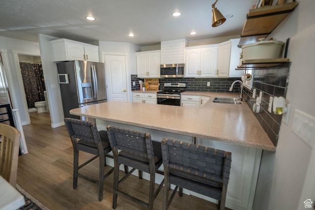 1536 E Mountain Rd, Logan, UT 84321 - kitchen with appliances with stainless steel finishes, a sink, a peninsula, tasteful backsplash, and white cabinetry