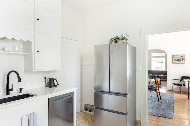 336 S Douglas St S, Salt Lake City, UT 84102 - kitchen featuring stainless steel appliances, a sink, white cabinetry, arched walkways, and light countertops