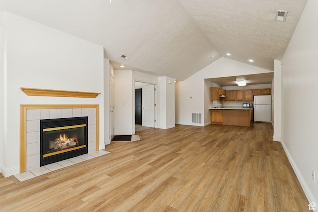 9362 S Abbey View Rd W, West Jordan, UT 84088 - unfurnished living room with a tile fireplace, light wood-style floors, lofted ceiling, baseboards, and recessed lighting