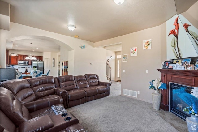6731 S Ticklegrass Rd W, West Jordan, UT 84081 - living area with arched walkways, light colored carpet, a glass covered fireplace, stairs, and a chandelier