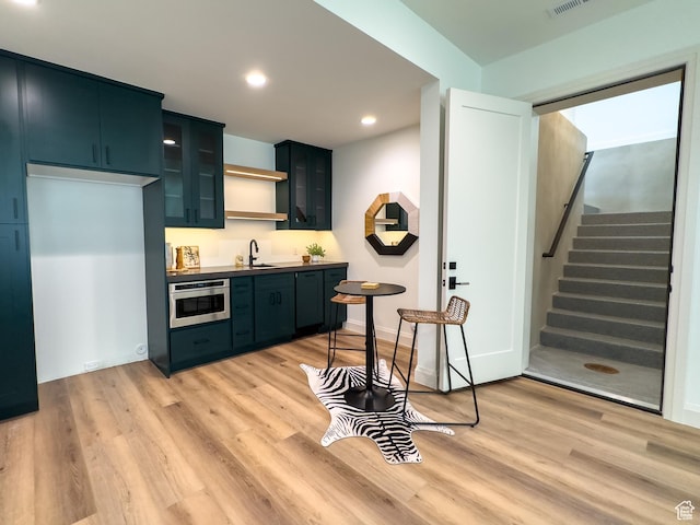 4893 W Ridge Rock Cir, Herriman, UT 84096 - kitchen featuring light wood-type flooring, wall oven, glass insert cabinets, a sink, and recessed lighting