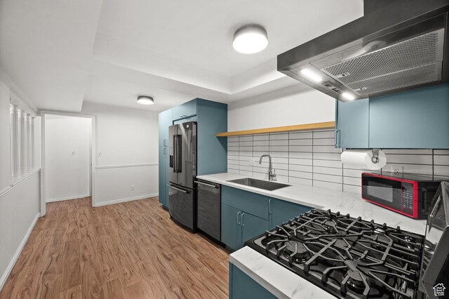 2220 E Murray Holladay Rd Unit 184, Holladay, UT 84117 - kitchen featuring wall chimney exhaust hood, stainless steel appliances, blue cabinetry, a sink, and light wood finished floors