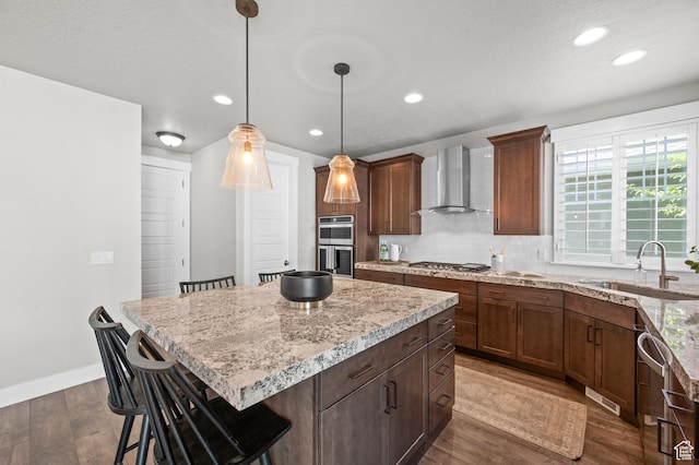 10685 S Dielsdorf Rd E, Sandy, UT 84092 - kitchen with wall chimney exhaust hood, a sink, stainless steel appliances, a breakfast bar, and dark wood finished floors