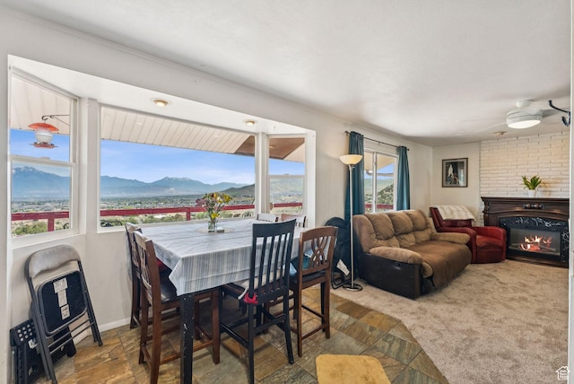 8043 W Hi Country Rd S, Herriman, UT 84096 - dining room featuring a glass covered fireplace, a mountain view, ceiling fan, and stone finish flooring