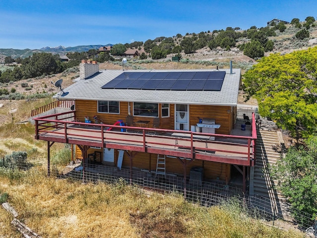 8043 W Hi Country Rd S, Herriman, UT 84096 - rear view of house with a deck with mountain view, a shingled roof, solar panels, and a chimney