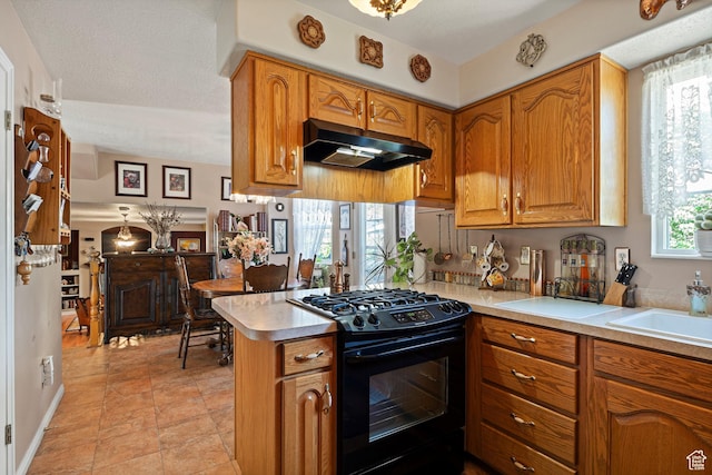 963 E 1275 N, Ogden, UT 84404 - kitchen featuring black gas range oven, under cabinet range hood, light countertops, brown cabinets, and a peninsula