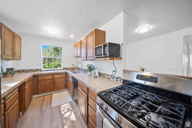 5111 S 1000 E, Murray, UT 84117 - kitchen with stainless steel appliances, a sink, light wood-style flooring, and brown cabinets
