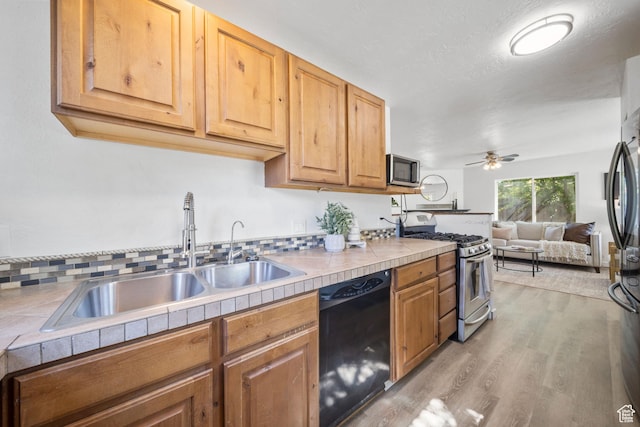 5111 S 1000 E, Murray, UT 84117 - kitchen with appliances with stainless steel finishes, a sink, tile counters, light wood finished floors, and a ceiling fan