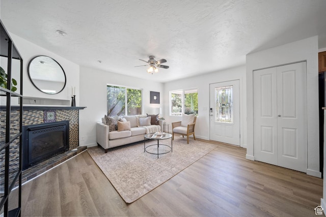 5111 S 1000 E, Murray, UT 84117 - living room with a tiled fireplace, wood finished floors, ceiling fan, baseboards, and a textured ceiling