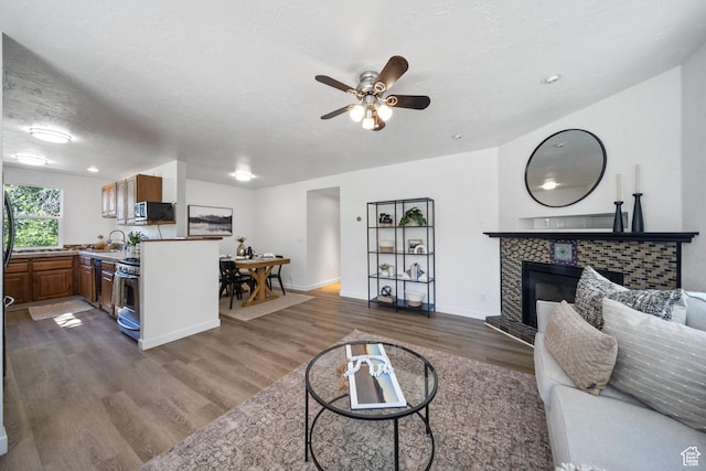 5111 S 1000 E, Murray, UT 84117 - living room with dark wood-style flooring, a tiled fireplace, a ceiling fan, baseboards, and a textured ceiling