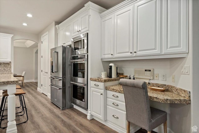 1784 E Ellerbeck Ln, Draper, UT 84020 - kitchen with stainless steel appliances, light wood-style floors, white cabinetry, arched walkways, and recessed lighting