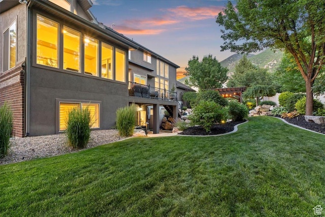 1784 E Ellerbeck Ln, Draper, UT 84020 - back of property at dusk with stucco siding, a lawn, and a balcony