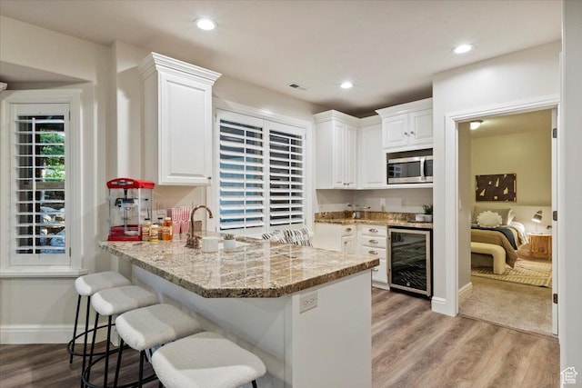1784 E Ellerbeck Ln, Draper, UT 84020 - kitchen featuring beverage cooler, stainless steel microwave, white cabinets, light wood finished floors, and recessed lighting